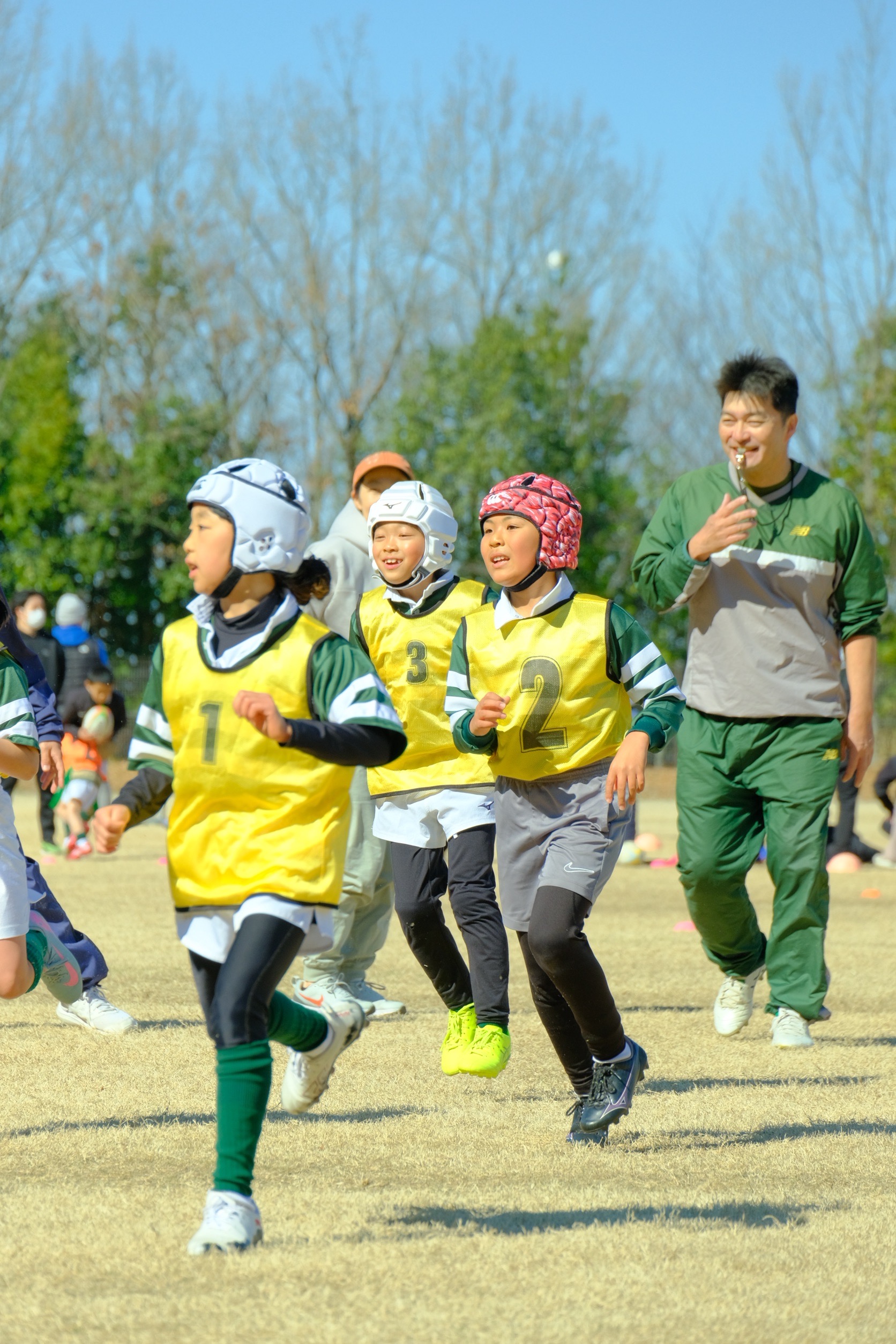 子どもたちがグラウンドでラグビーの練習をしている様子